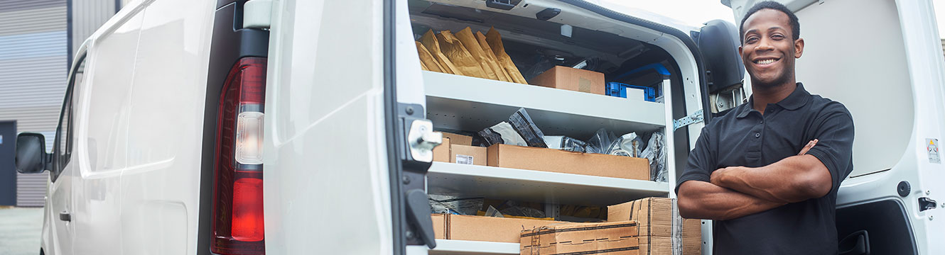 Man standing next to the back of an open van with boxes and packaging inside it