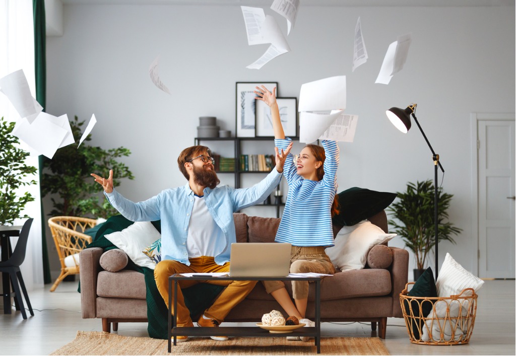 couple sitting on the couch tossing papers in the air.