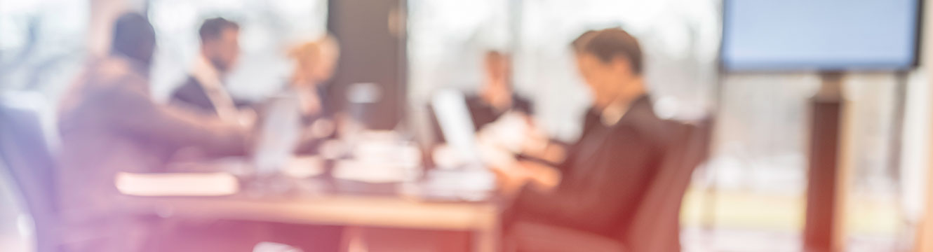 Blurry shot of business people at a conference table in suits