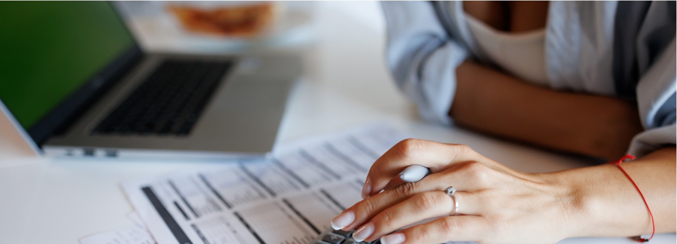 Hand of a women hovering over bills holding a pen
