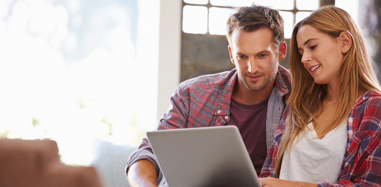 Young couple looking at laptop wearing flannel shirts